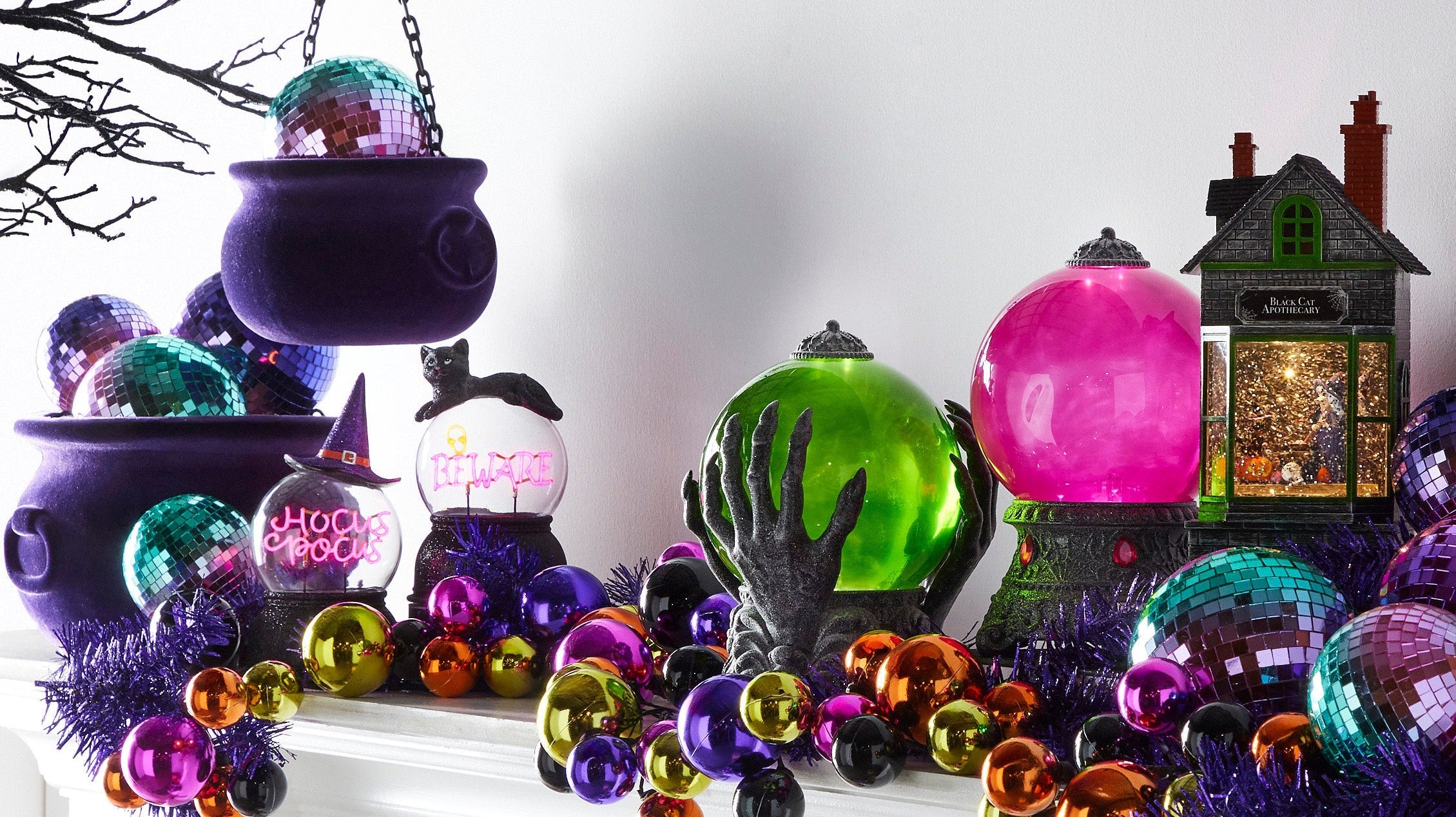 olorful Halloween mantel with cauldrons, crystal balls, garland.