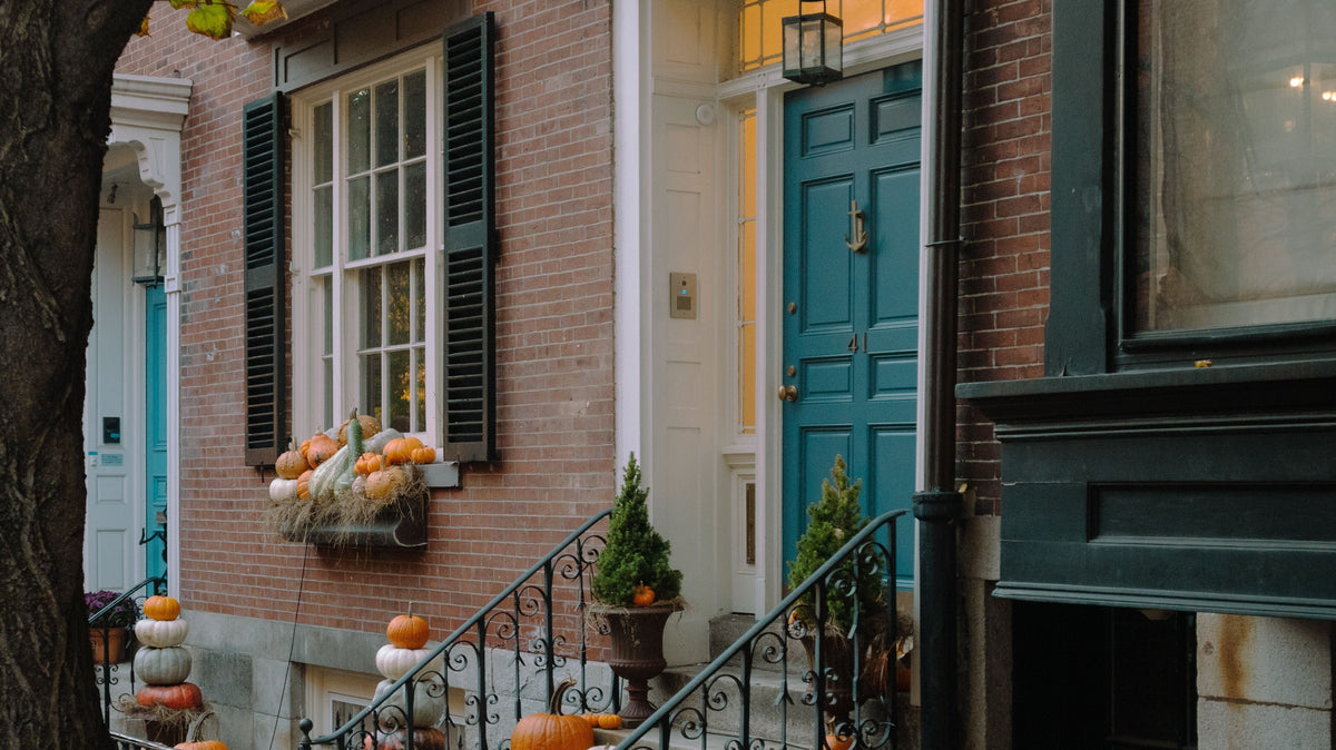 Brick townhouse entrance decorated with Halloween pumpkins.