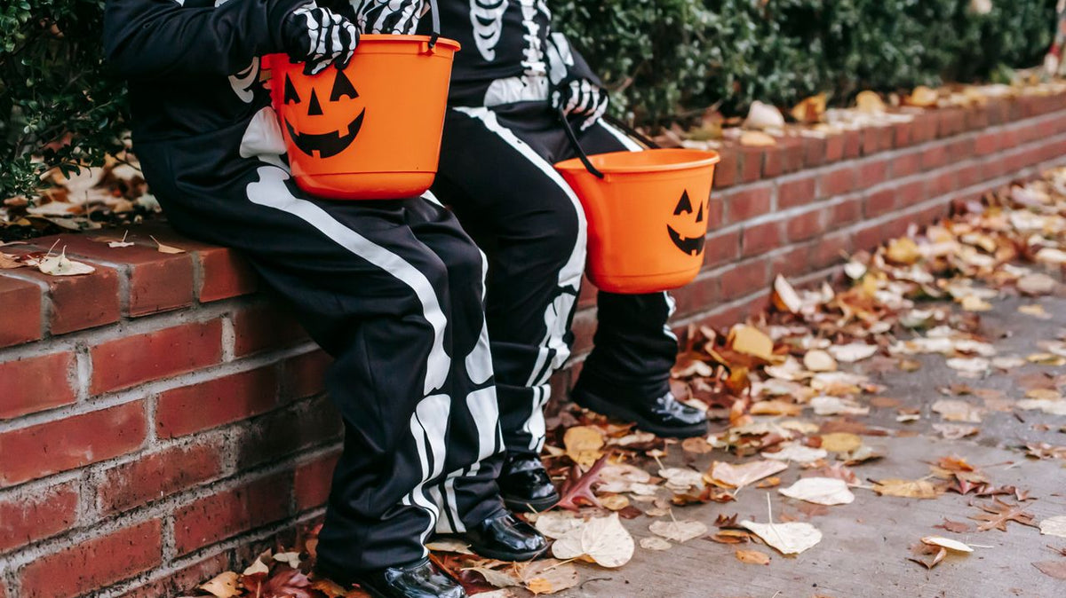 Kids in Halloween costumes with jack-o'-lantern candy buckets.
