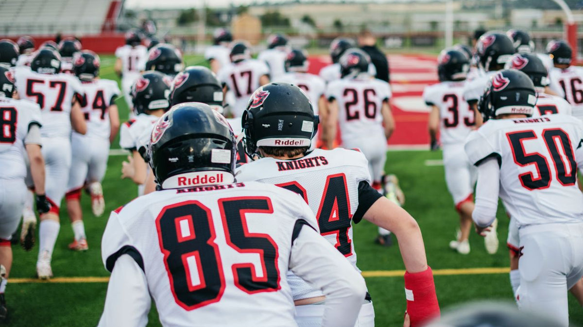 Football players jog onto the field together.