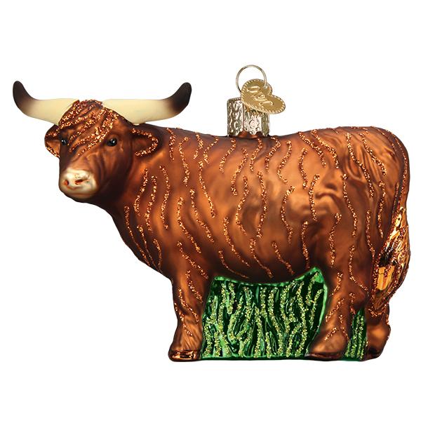 Brown glass Highland cow Christmas ornament with long horns, glittery fur texture, and a green grass base.