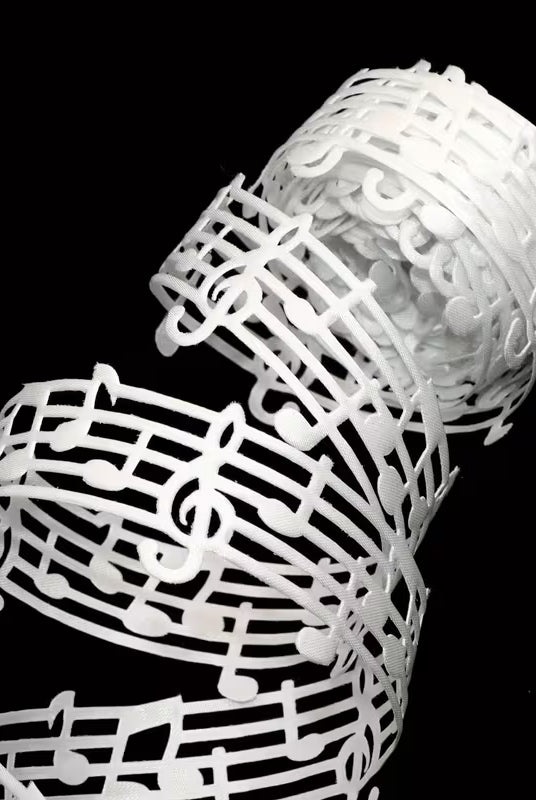 Close-up of white music note lace ribbon detail on black background