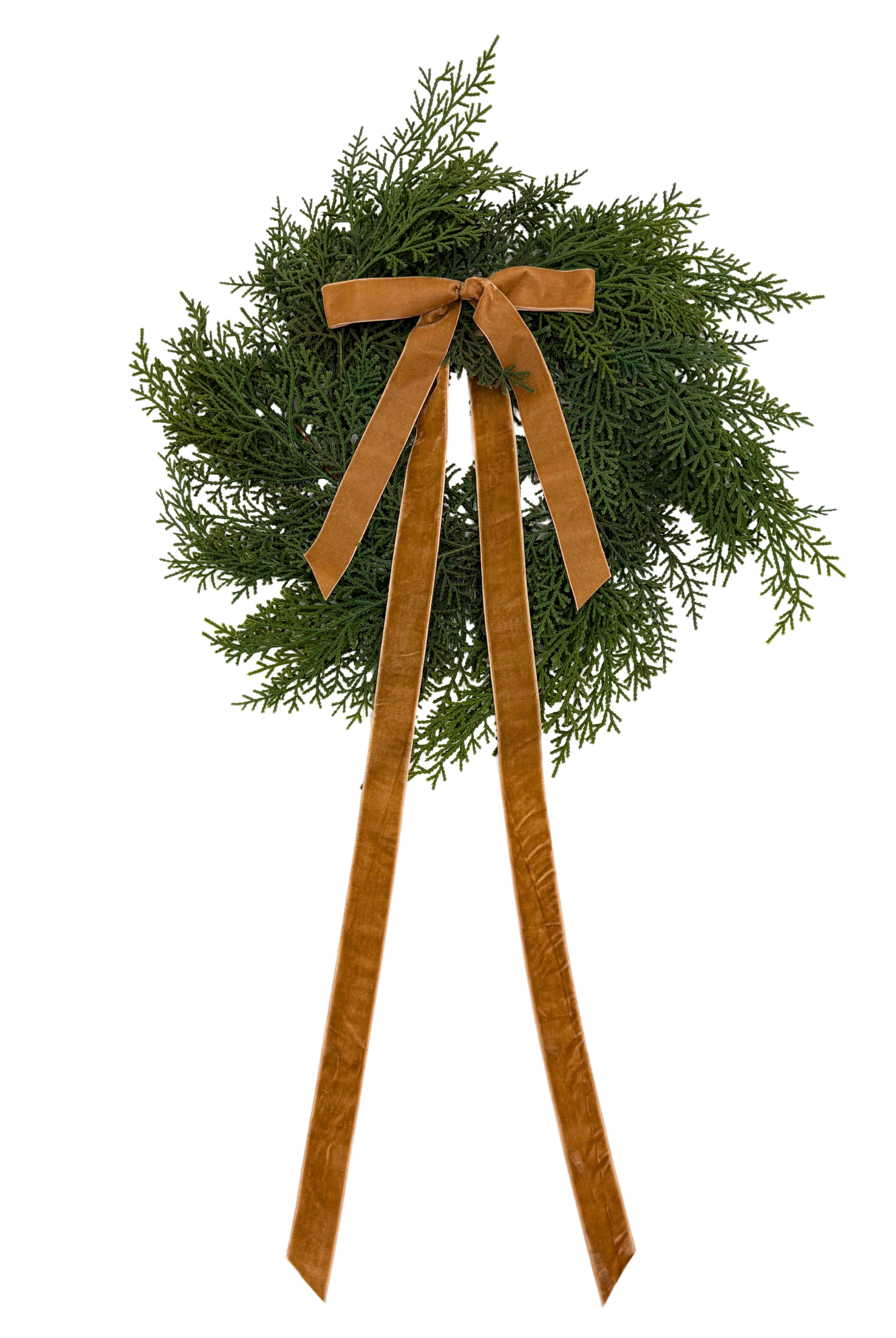 Mini faux cedar Christmas wreath with a long, elegant caramel velvet ribbon bow on a white background.
