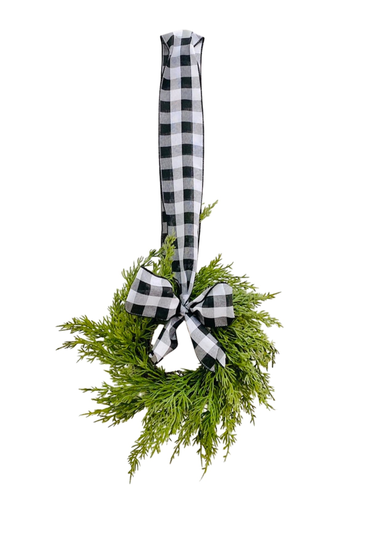 Mini artificial cedar Christmas wreath with a black and white buffalo check ribbon bow, hanging against a white background.