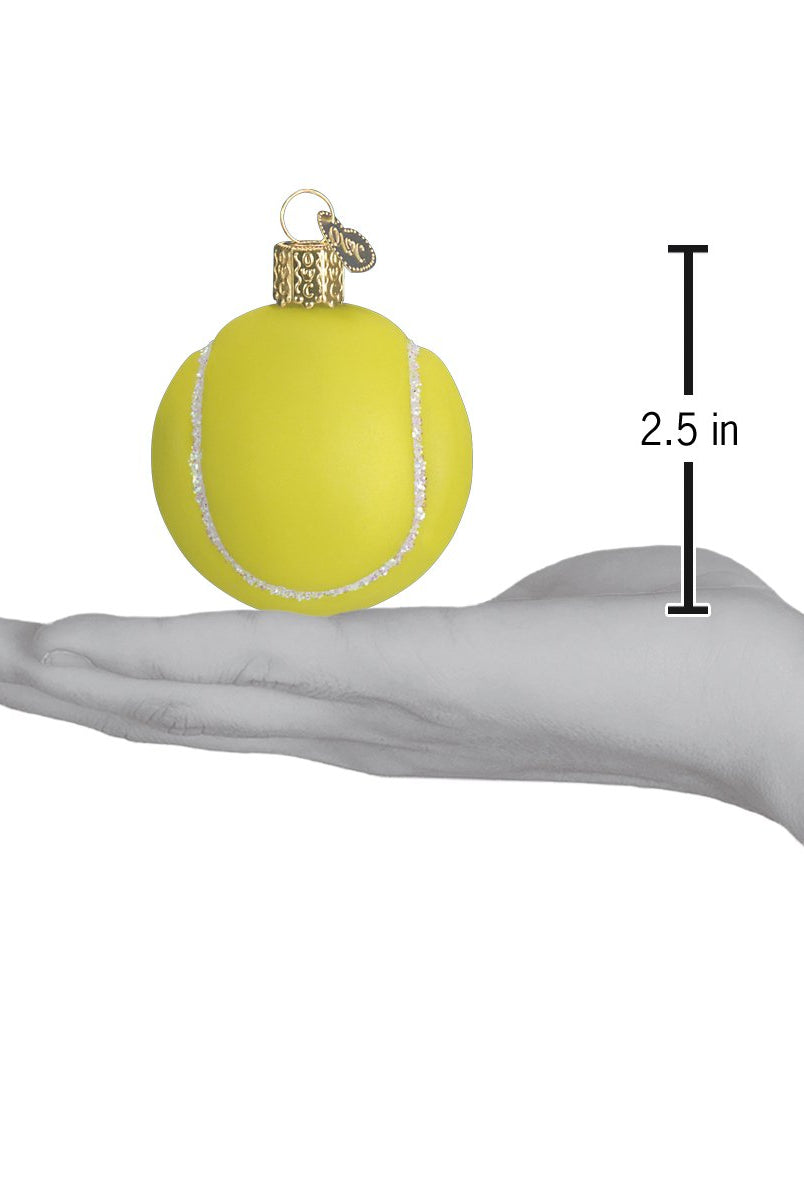 Hand-held 2.5-inch glass tennis ball ornament with bright yellow paint, glittery white seams, and a gold hanging cap.