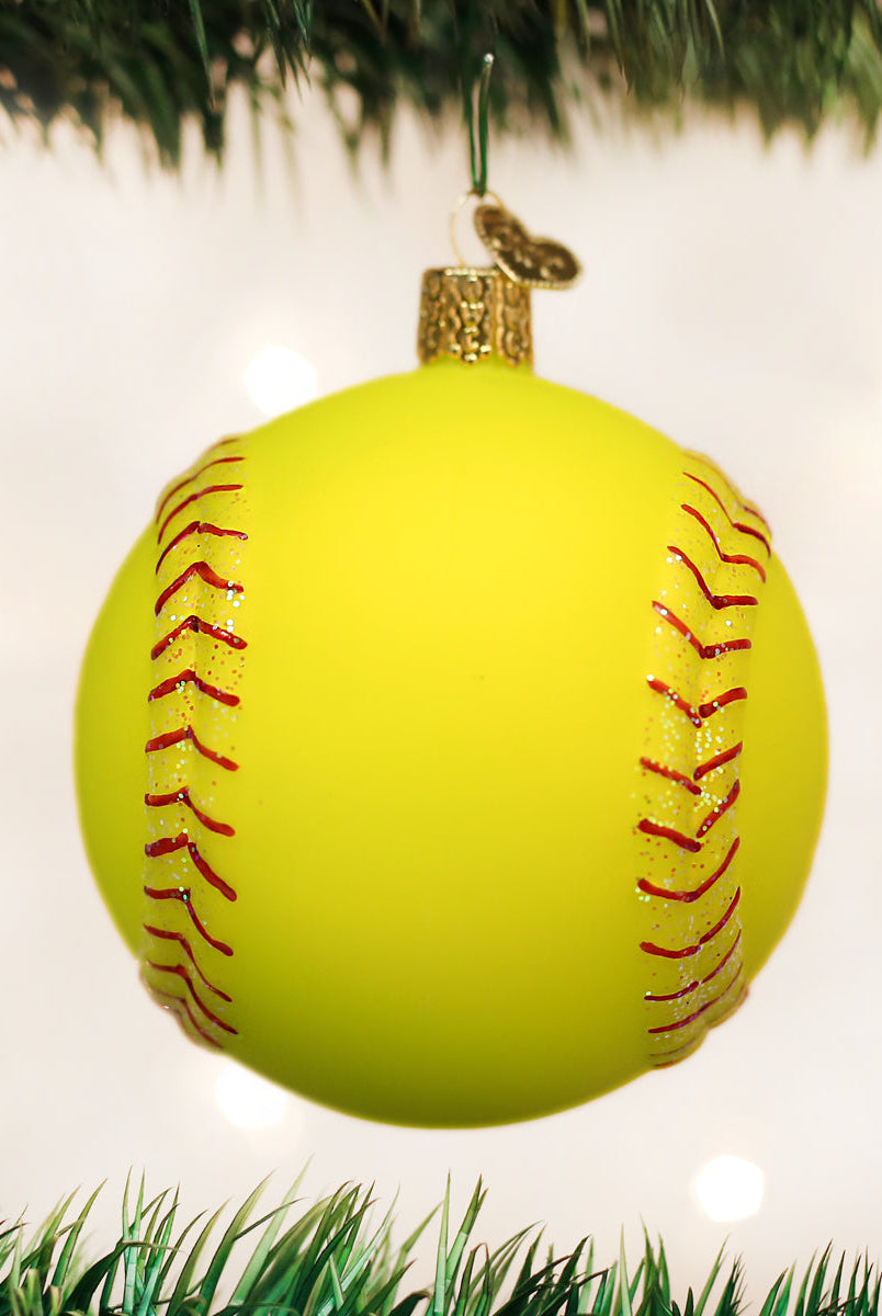 Bright yellow glass softball Christmas ornament with red glitter stitching hanging from a tree branch.