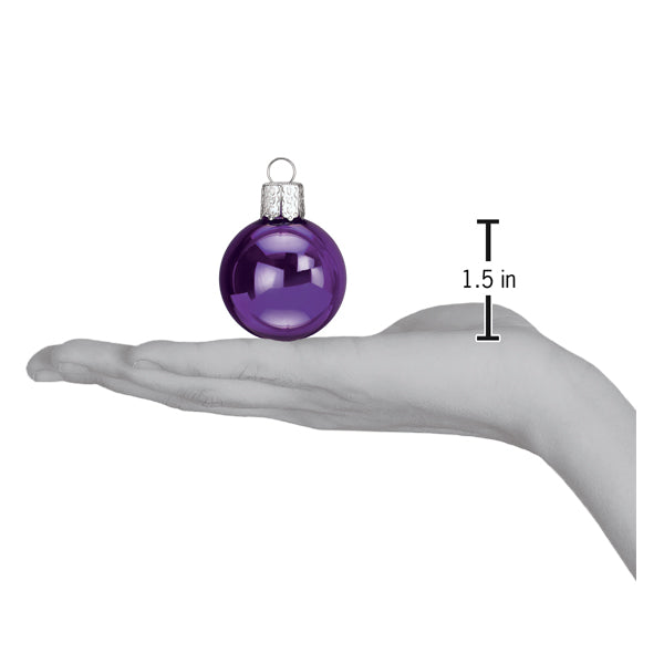 Shiny purple 1.5-inch Halloween ornament ball held in a hand to show scale.