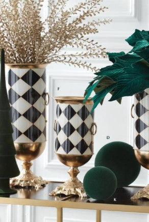 Black and white harlequin check urn vases with gold pedestal bases and side handles, styled with holiday florals.