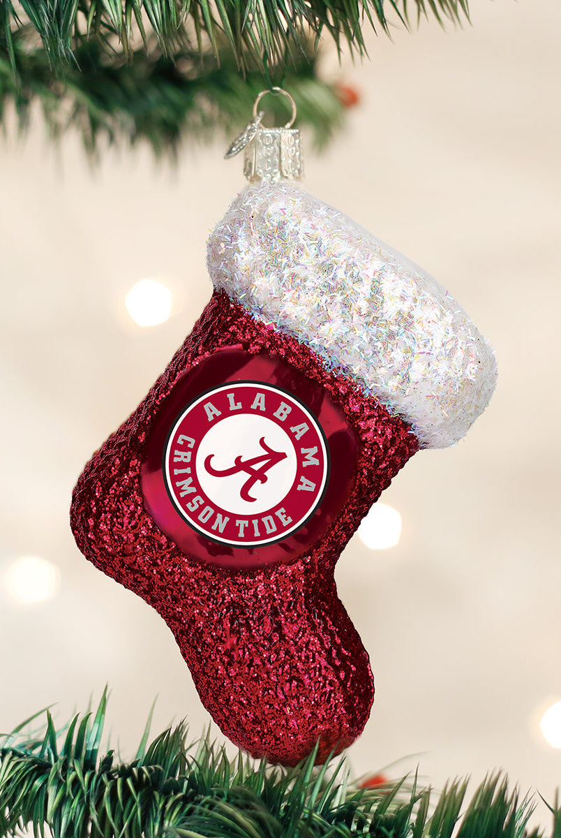 Red glittery Alabama Crimson Tide stocking ornament with a white iridescent cuff hanging on a Christmas tree.