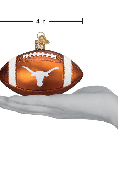 Burnt orange glass football ornament featuring the white Texas Longhorns logo, held in a hand for scale.