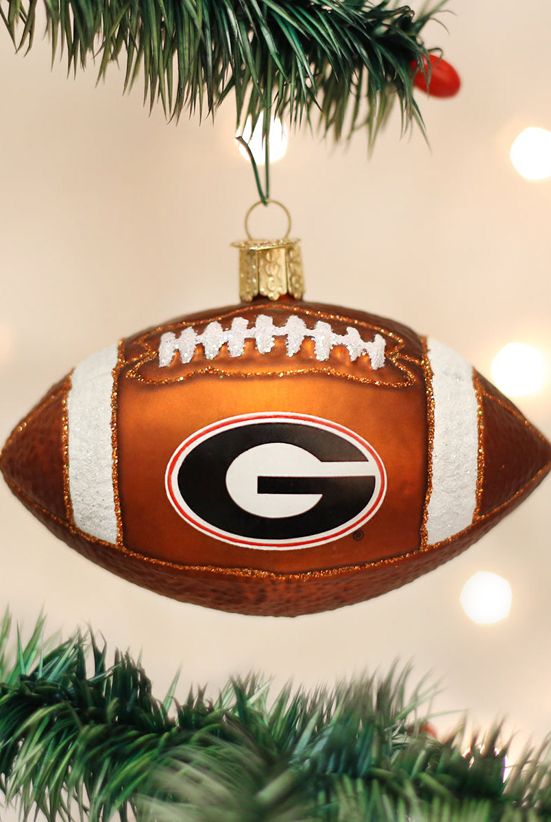 Glass Georgia Bulldogs football ornament with a brown textured finish, white glitter laces, and the team G logo.