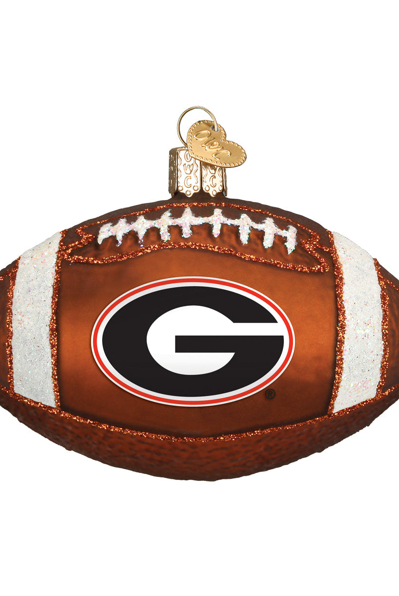 Brown glass football ornament featuring the Georgia Bulldogs G logo, white glitter accents, and a gold heart charm.