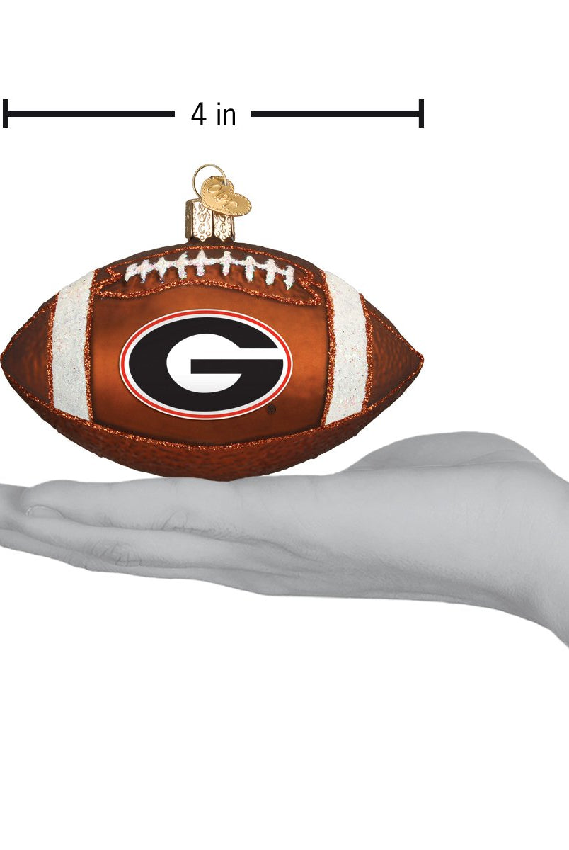 4-inch brown glass Georgia Bulldogs football ornament with white laces and team logo held in a hand.