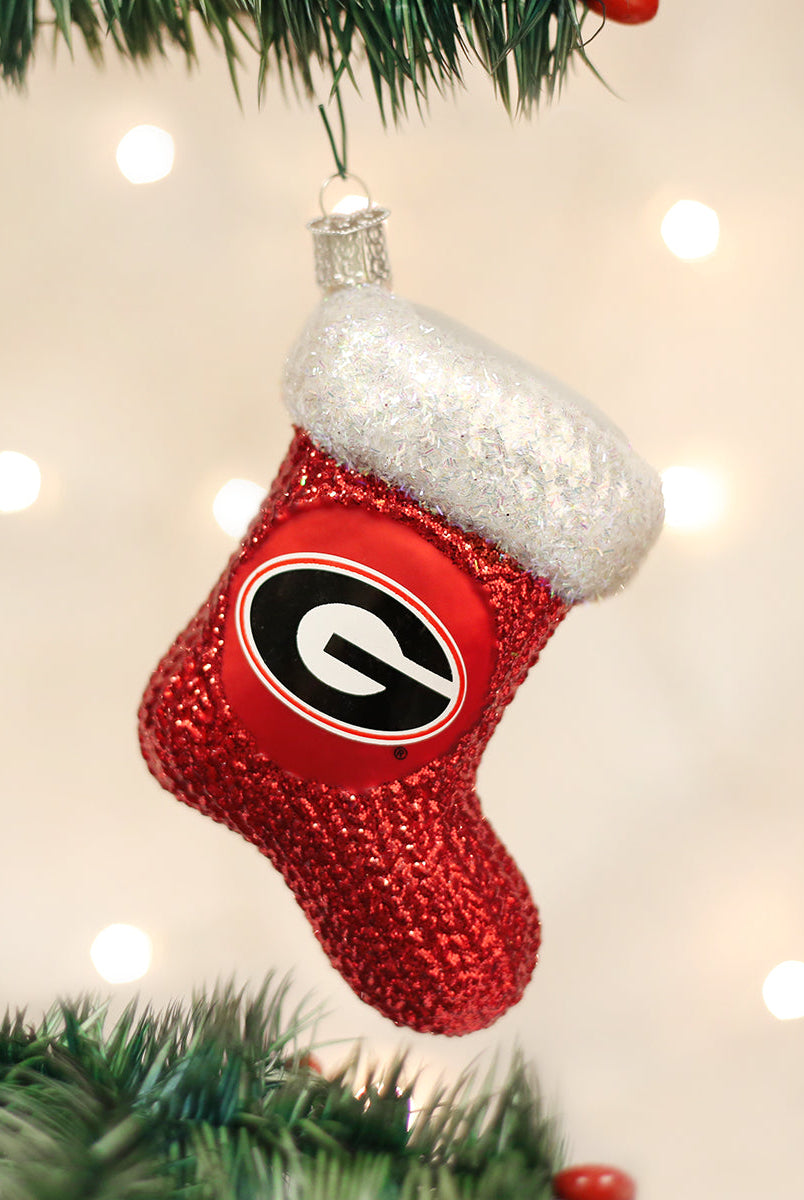 Red glittery Georgia Bulldogs stocking ornament with a white faux fur cuff hanging on a Christmas tree.