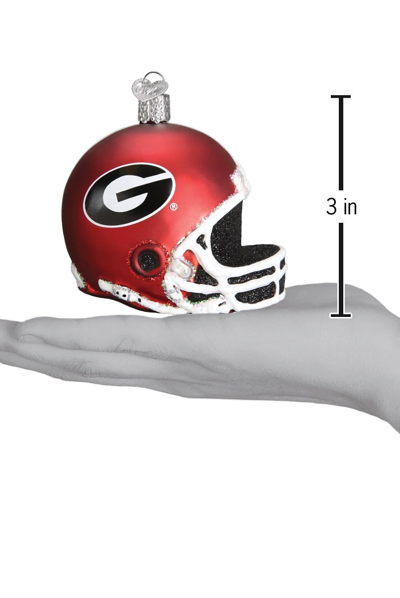 3-inch red Georgia Bulldogs glass football helmet ornament with black and white logo held in a hand.