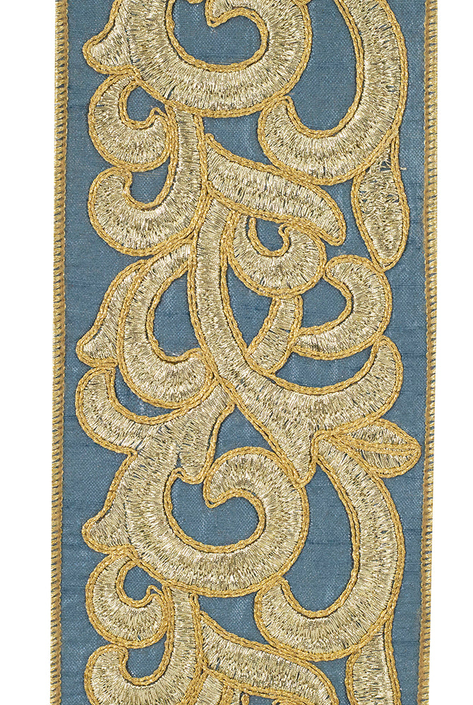 Blue fabric ribbon featuring intricate gold metallic scrollwork embroidery and finished edges.