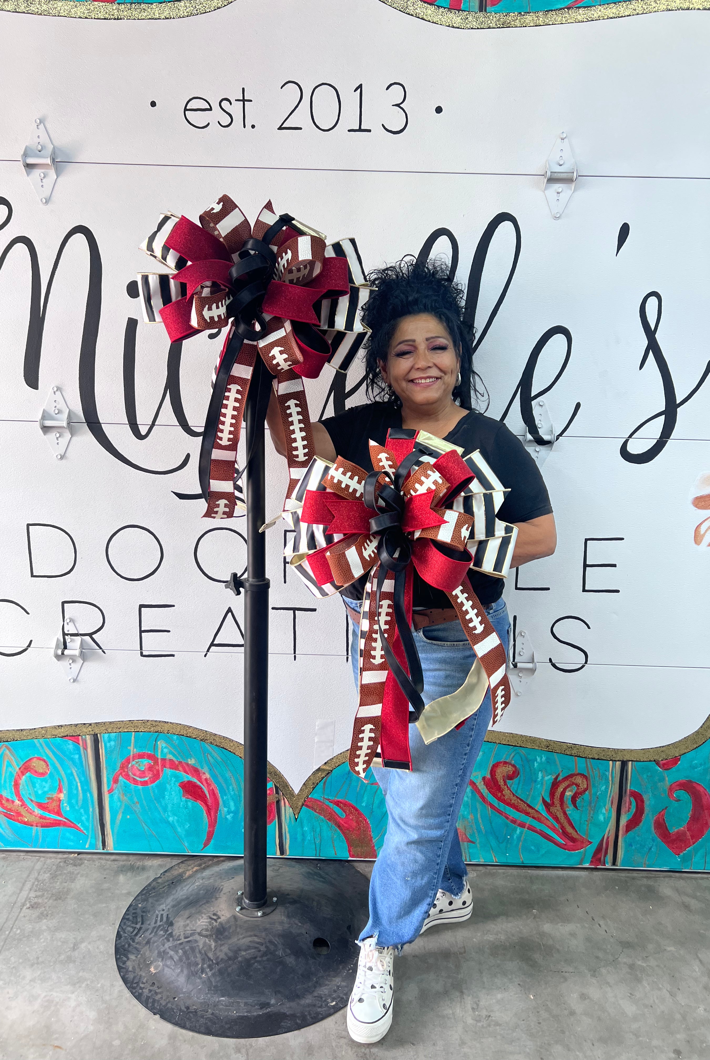 Large red and black football-themed decorative bow with glitter accents and long ribbon tails for sports decor.