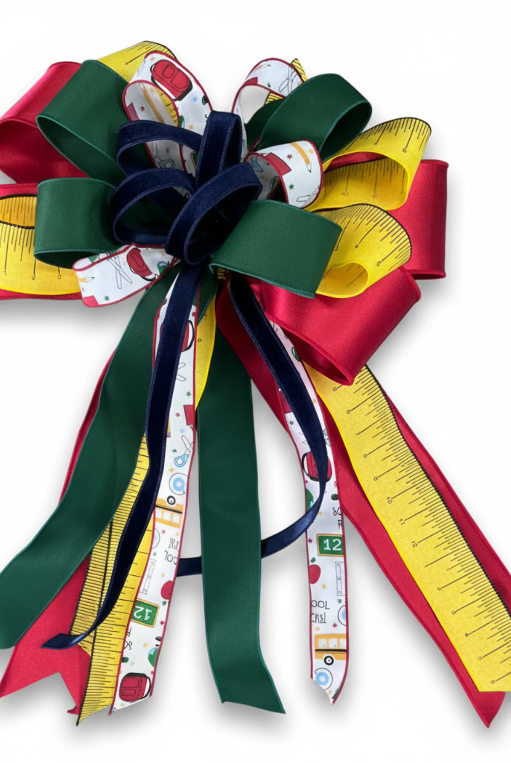 Large back-to-school bow featuring red, green, and yellow ribbon with ruler, school supply, and bus patterns.