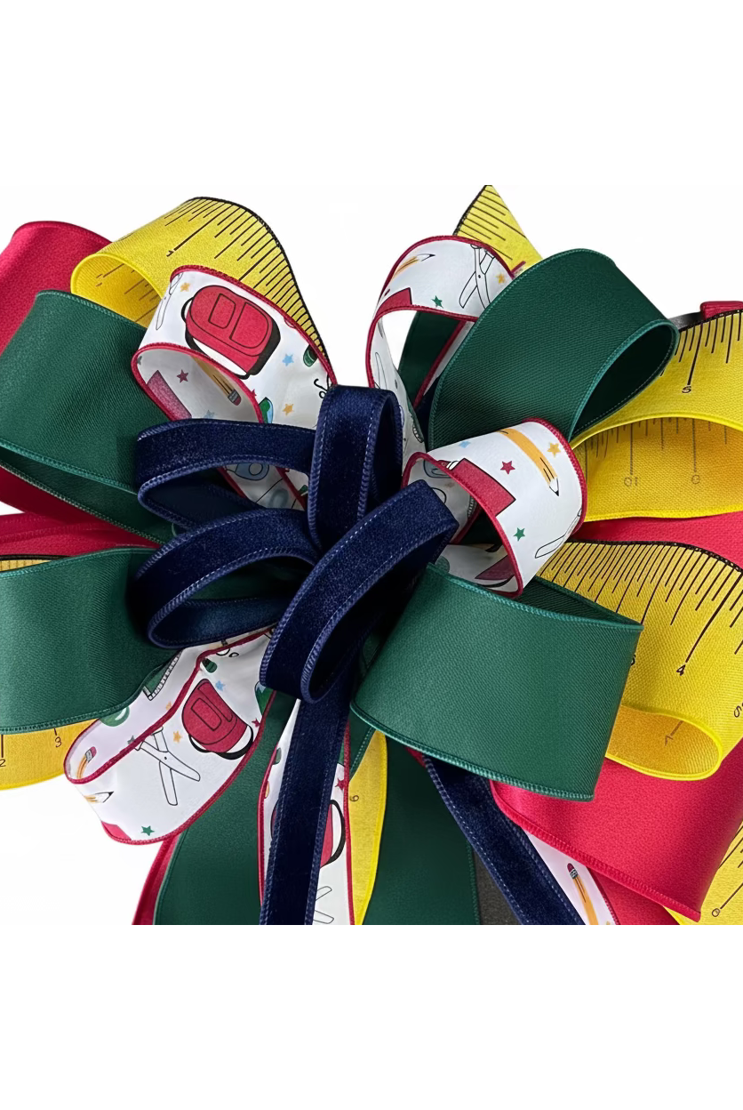 Large back-to-school bow featuring red, green, and yellow ribbons with school supply patterns and a navy velvet center.