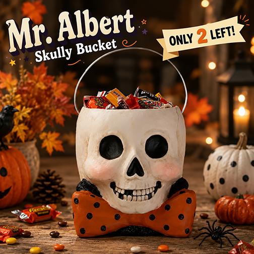 Bethany Lowe paper mache skull bucket with an orange glitter polka-dot bow tie, filled with Halloween candy.