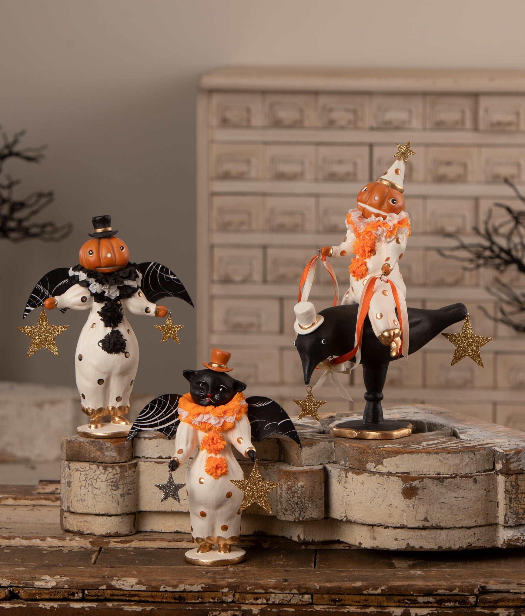 Vintage-style Halloween decor featuring a pumpkin-headed clown riding a black crow with glittered stars and crepe paper.