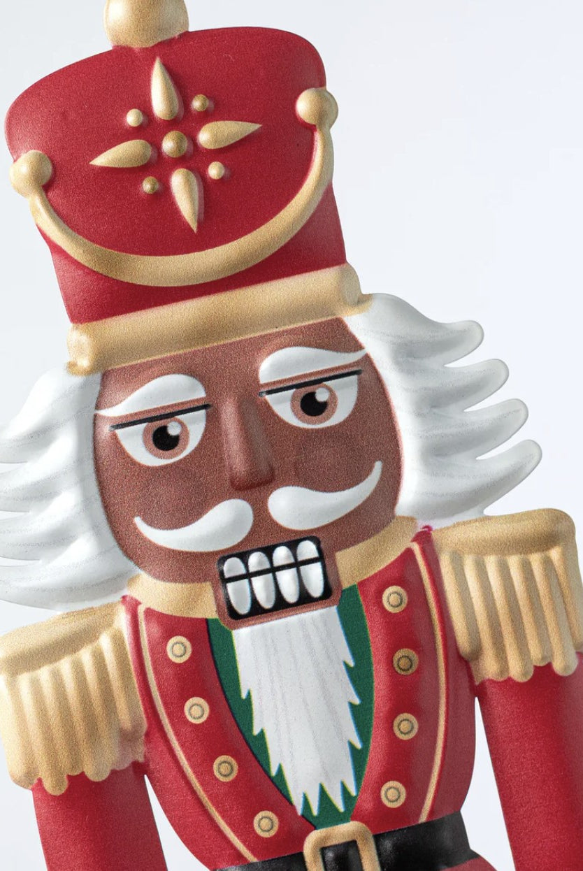 12-inch embossed metal nutcracker sign featuring a dark skin soldier in a red and gold uniform with white hair.