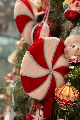 Red and white swirled peppermint lollipop stem ornament on Christmas tree