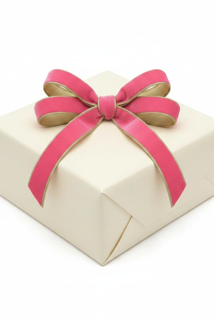 Pink lemonade velvet ribbon with gold dupioni backing and metallic trim tied in a bow on a cream gift box.