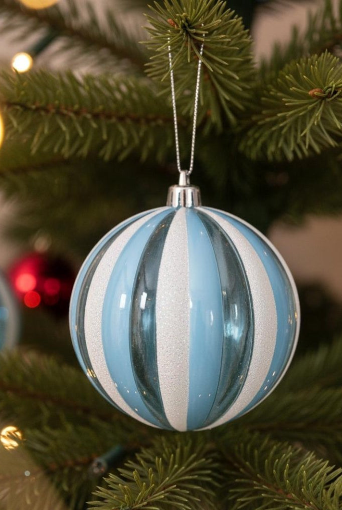 Blue and white striped holiday ornament on Christmas tree branch