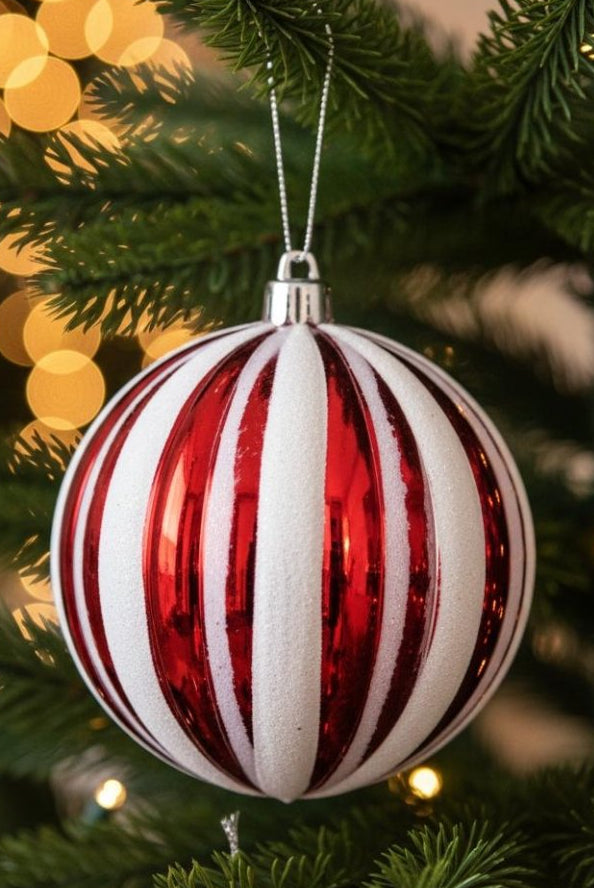 Red and white candy stripe ornament ball hanging on Christmas tree