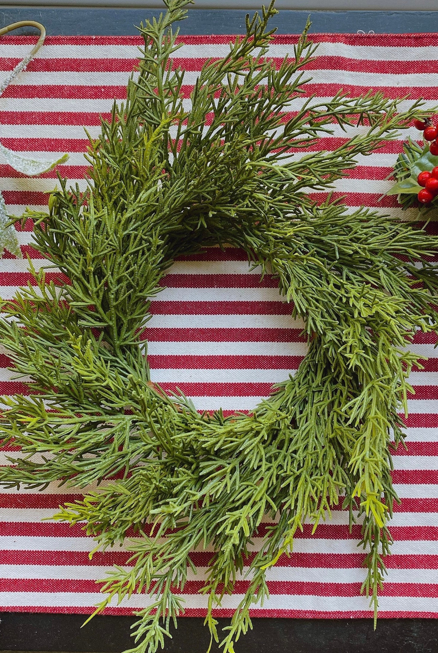 14-inch faux cedar mini Christmas wreath with realistic green foliage on a red and white striped farmhouse background.