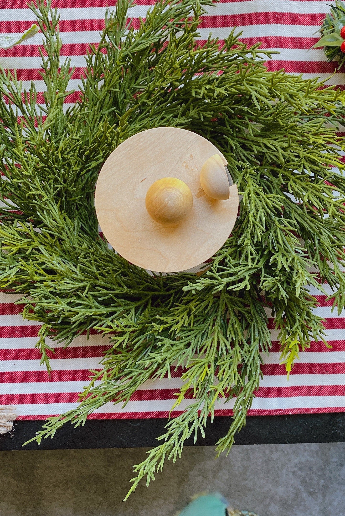 14-inch faux cedar mini Christmas wreath with green foliage on a red and white striped table runner.