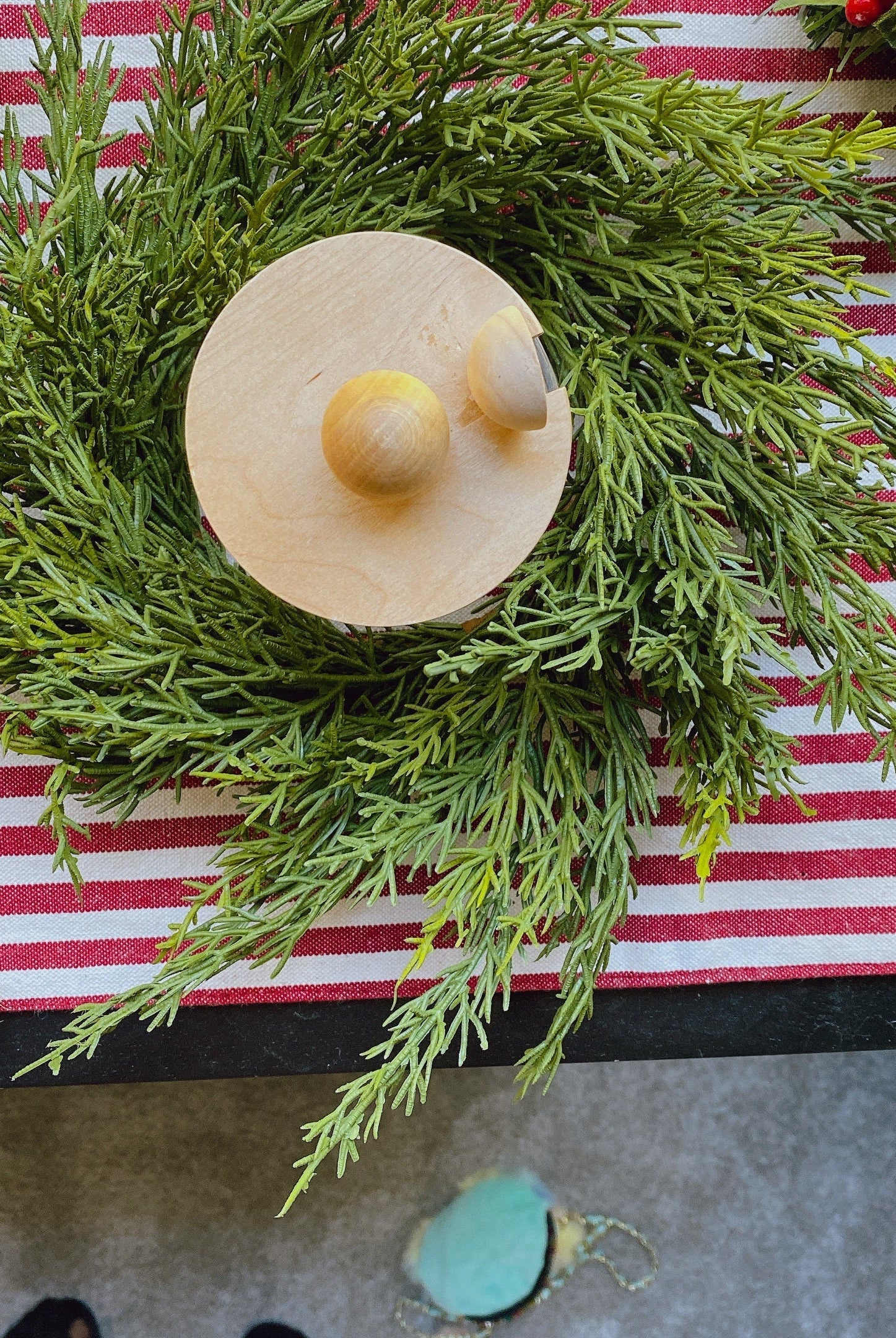 14-inch faux cedar mini Christmas wreath with a wooden accent on a red and white striped table runner.
