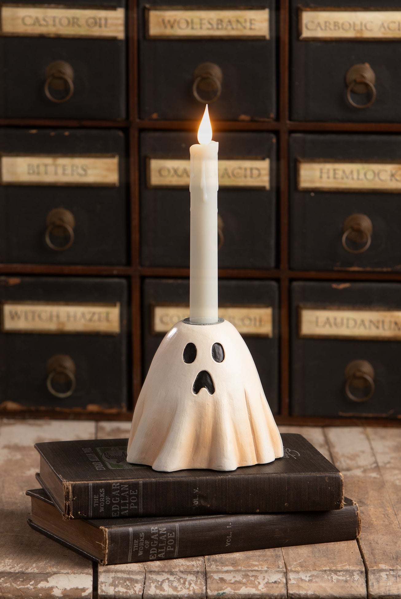 Vintage-style hand-painted resin ghost candlestick holder with a surprised expression, displayed on antique books.