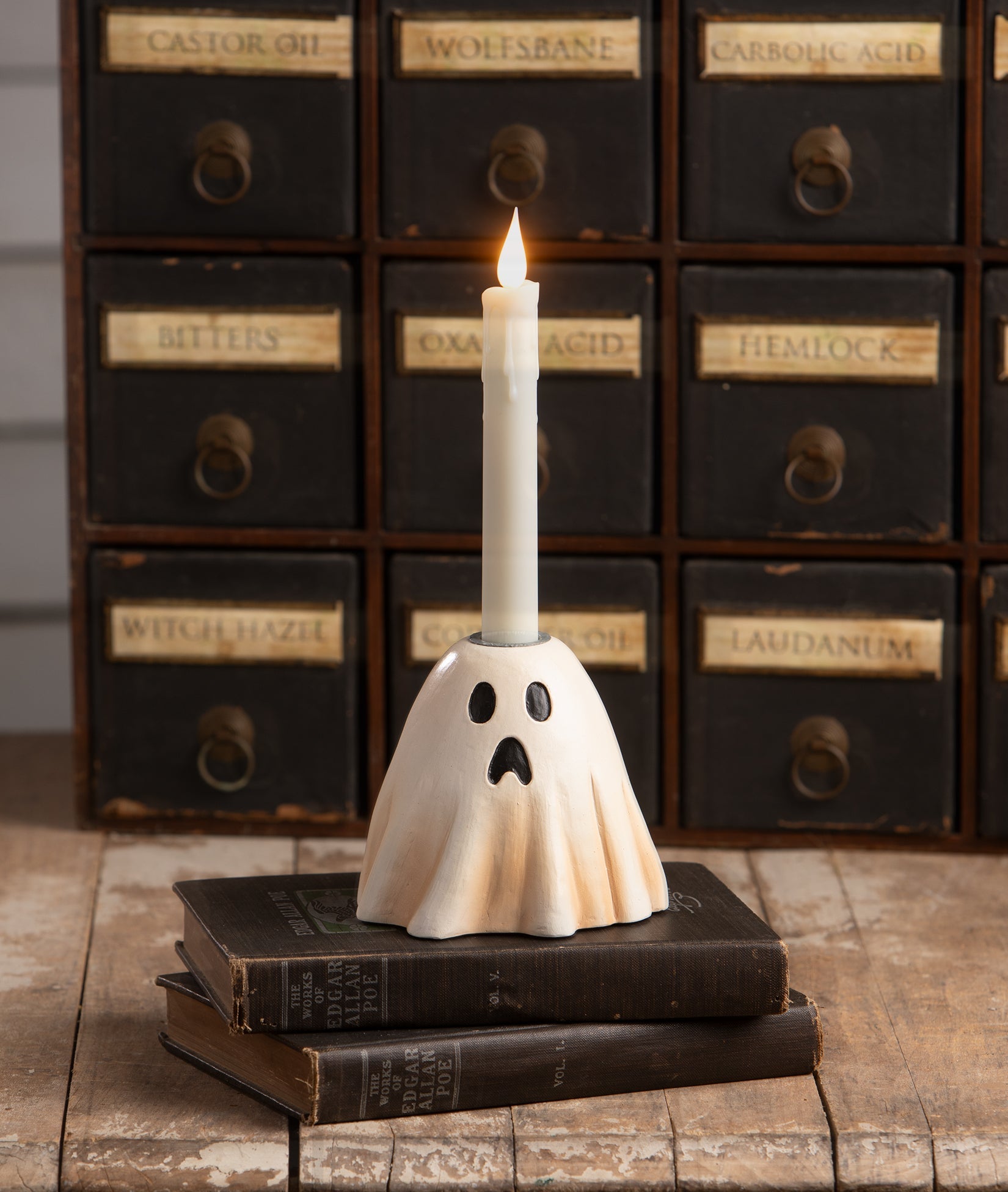 Vintage-style hand-painted resin ghost candlestick holder with a surprised expression, displayed on antique books.