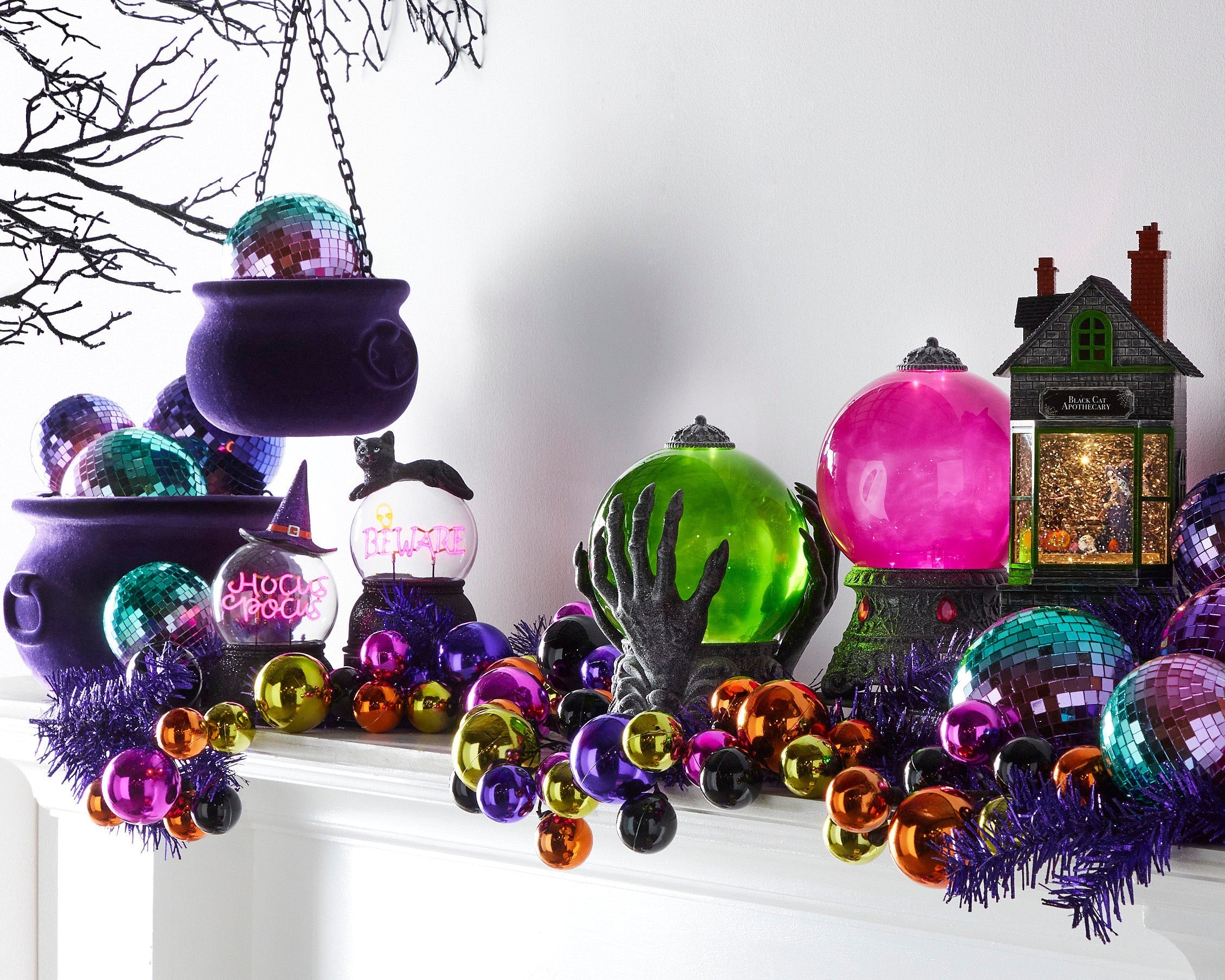 olorful Halloween mantel with cauldrons, crystal balls, garland.