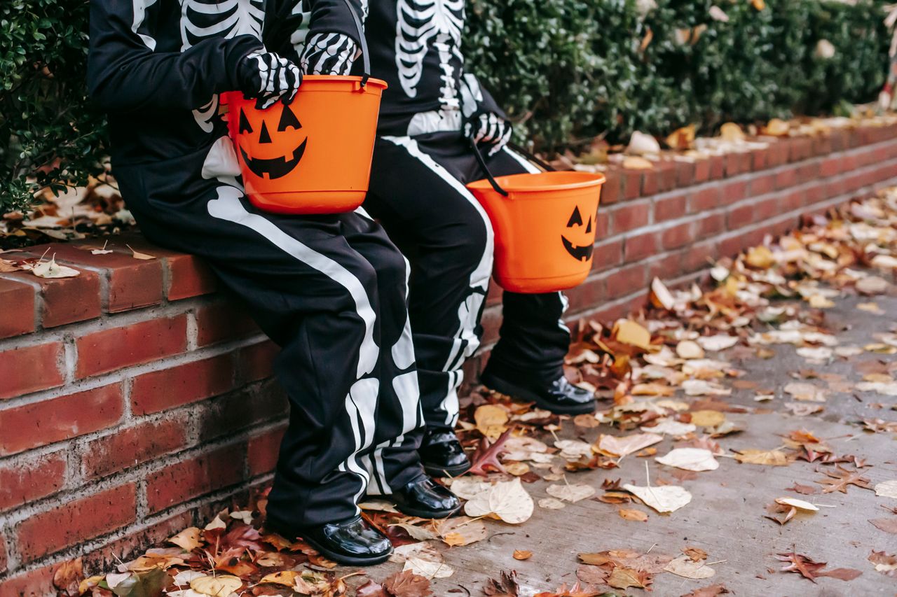 Kids in Halloween costumes with jack-o'-lantern candy buckets. 