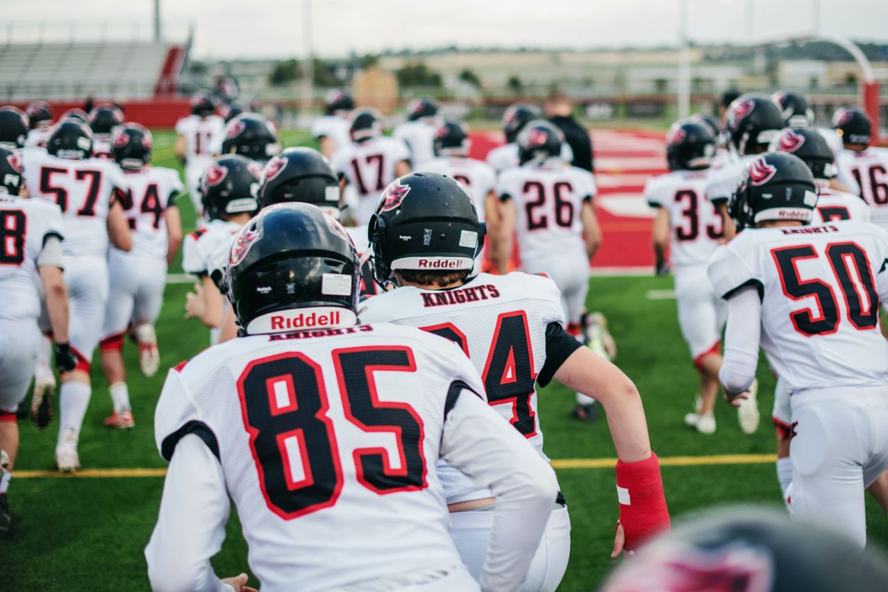 Football players jog onto the field together.