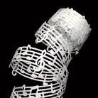 Close-up of white music note lace ribbon detail on black background