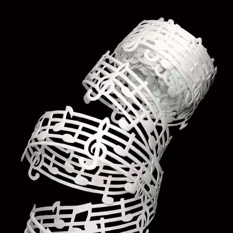 Close-up of white music note lace ribbon detail on black background