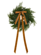 Mini faux cedar Christmas wreath with a long, elegant caramel velvet ribbon bow on a white background.