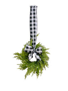 Mini artificial cedar Christmas wreath with a black and white buffalo check ribbon bow, hanging against a white background.