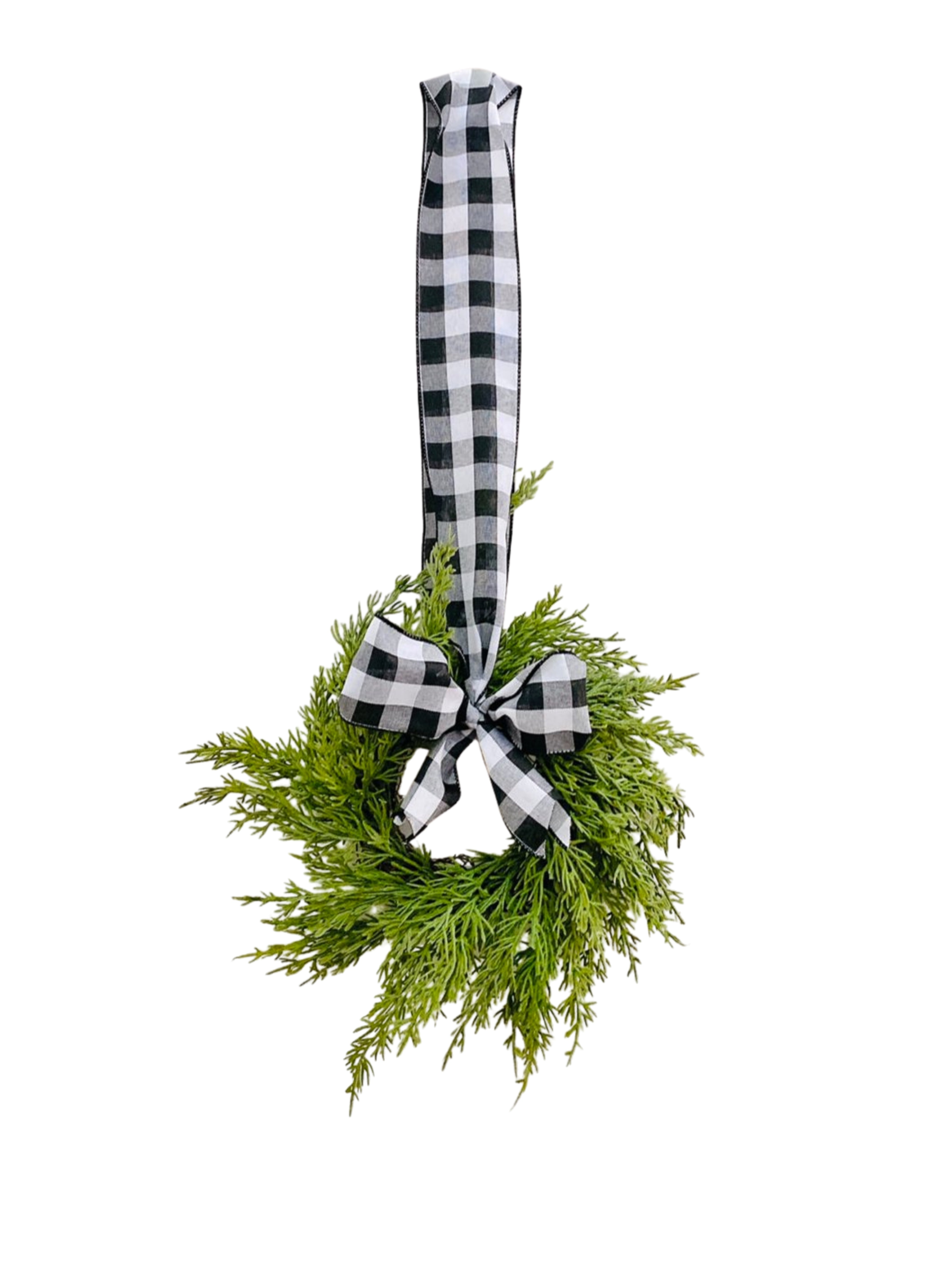 Mini artificial cedar Christmas wreath with a black and white buffalo check ribbon bow, hanging against a white background.