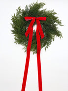 Mini Christmas cedar wreath with long red velvet ribbon for farmhouse cabinet or holiday home decor.