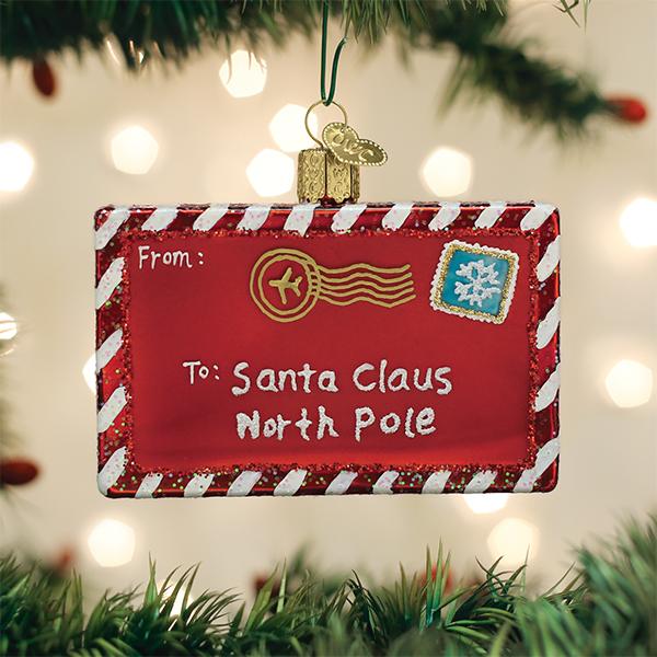 Red glass ornament shaped like a letter to Santa with white and red striped borders, gold postmark, and snowflake stamp.