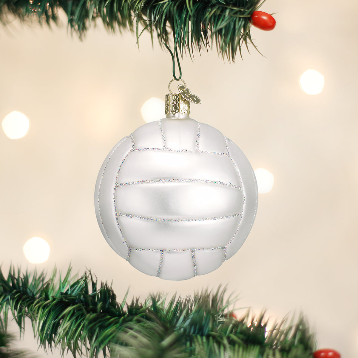 Mouth-blown glass volleyball ornament in matte white with silver glitter accents hanging on a Christmas tree.
