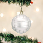 Mouth-blown glass volleyball ornament in matte white with silver glitter accents hanging on a Christmas tree.