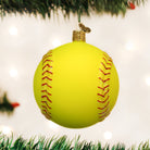 Bright yellow glass softball Christmas ornament with red glitter stitching hanging from a tree branch.