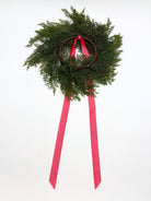 Mini cedar Christmas wreath on a twig base with long, elegant red ribbons hanging down against a white background.