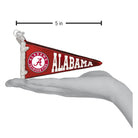 5-inch red glass Alabama Crimson Tide pennant ornament with white logo and lettering held in a hand.